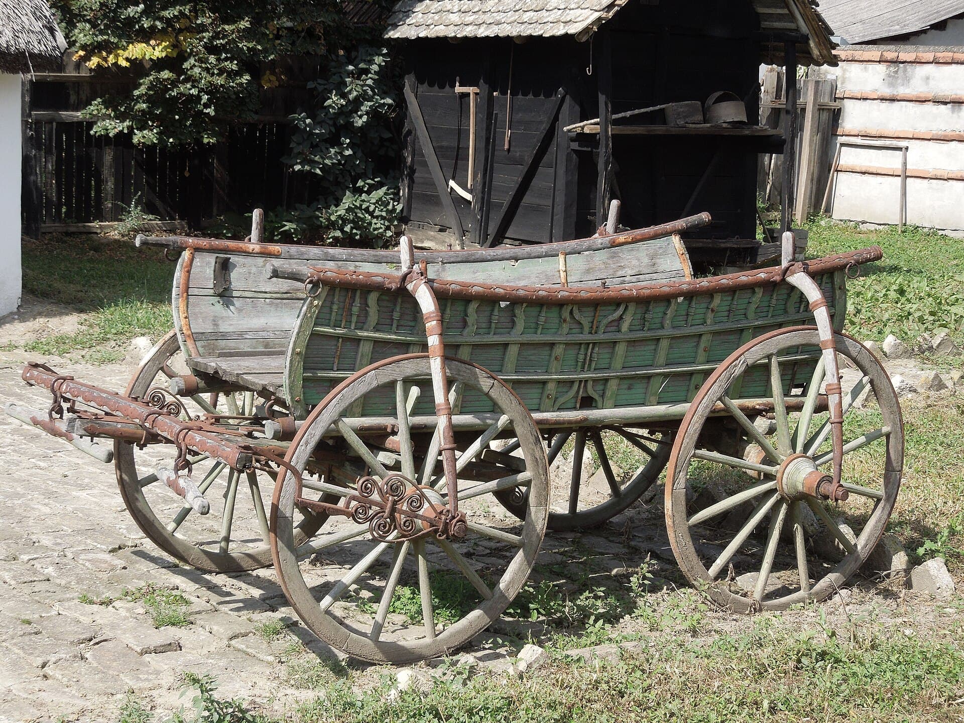 An old horse-drawn wagon parked outdoors in a rural setting.