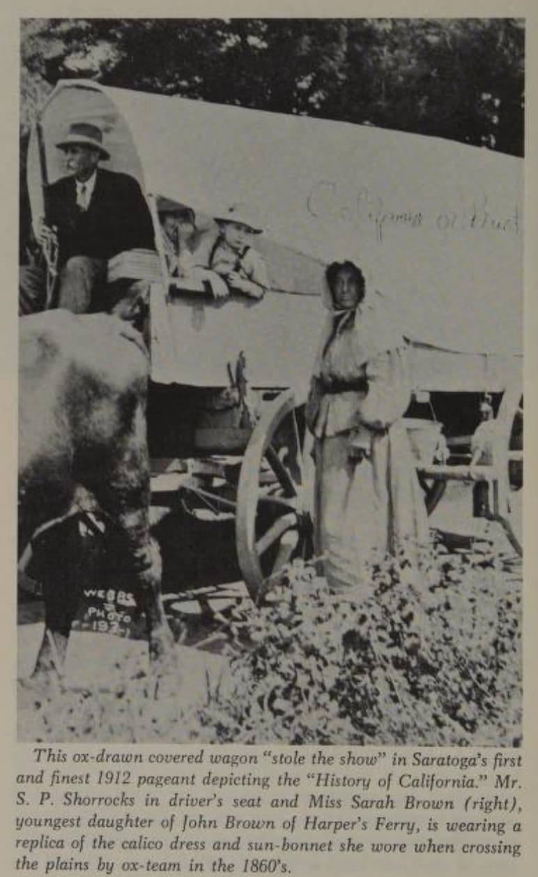 A replica prairie schooner photographed in context — what the wagons of the trails looked like alongside their drivers.