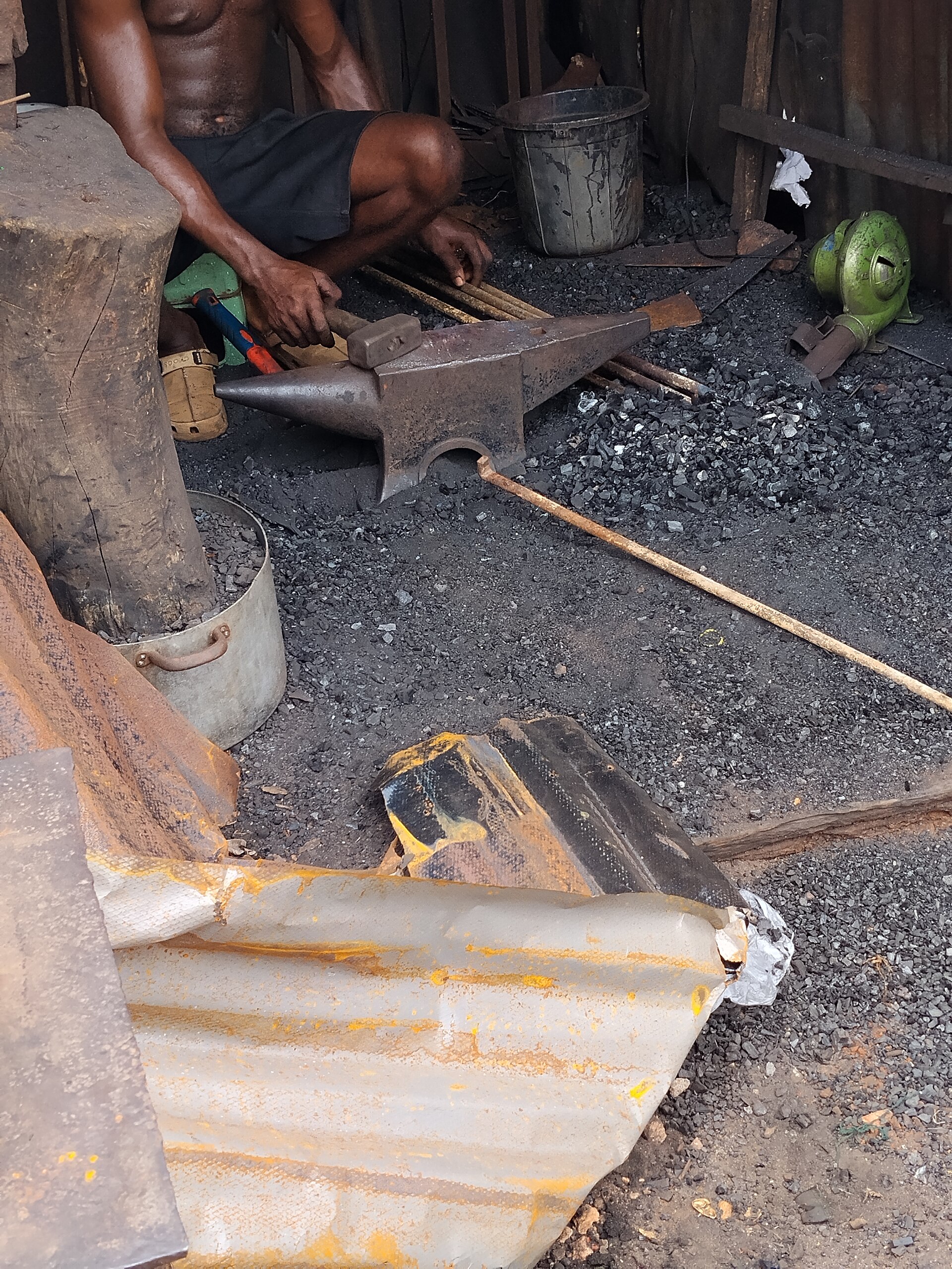 A blacksmith hammering hot iron on an anvil — sparks and smoke.