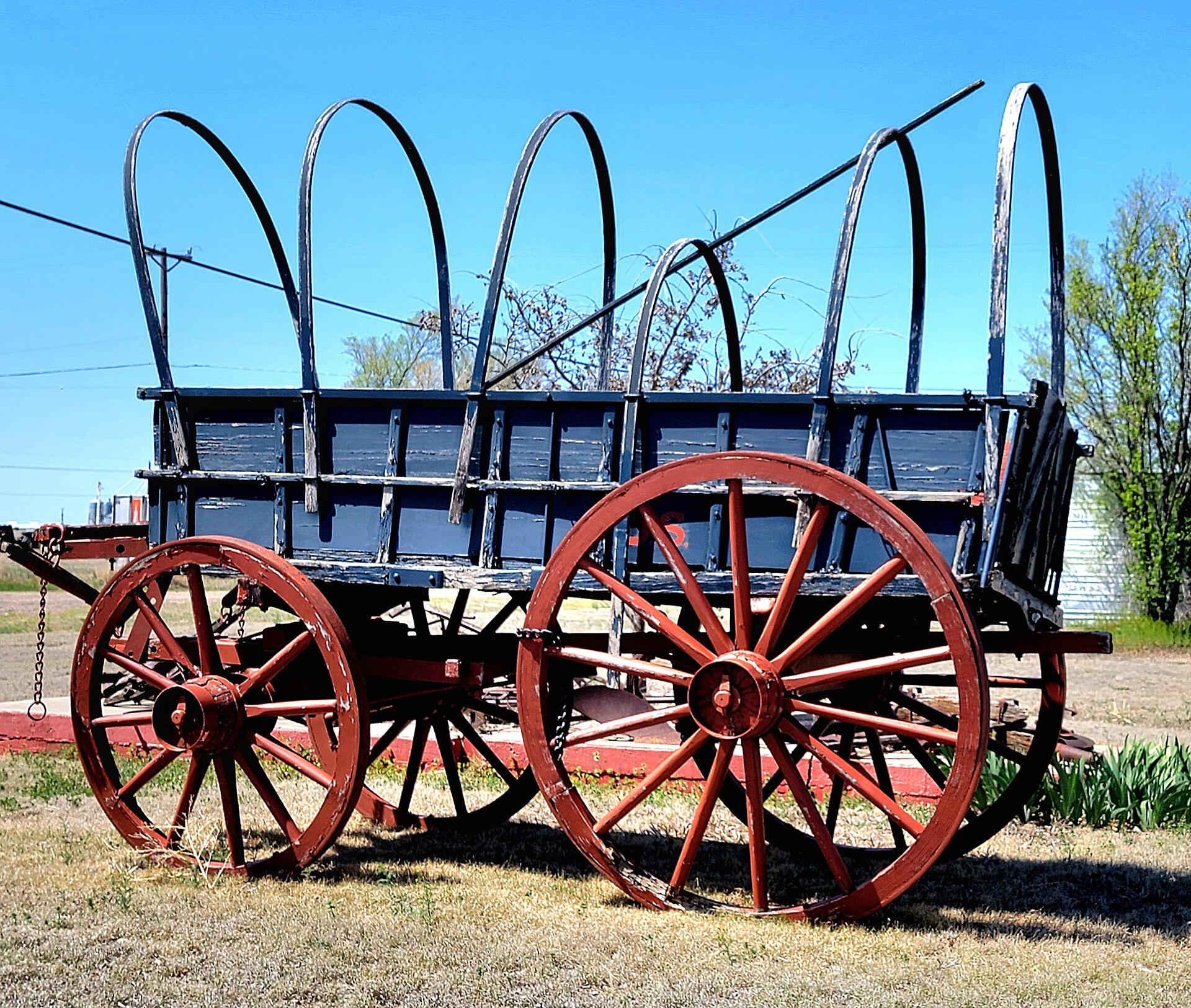 A Conestoga wagon parked outside in Vega, Texas — restored, in full sun.