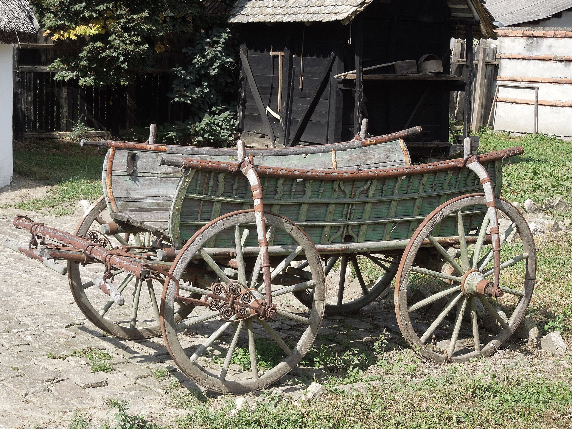 An old horse-drawn wagon parked outdoors in a rural setting.